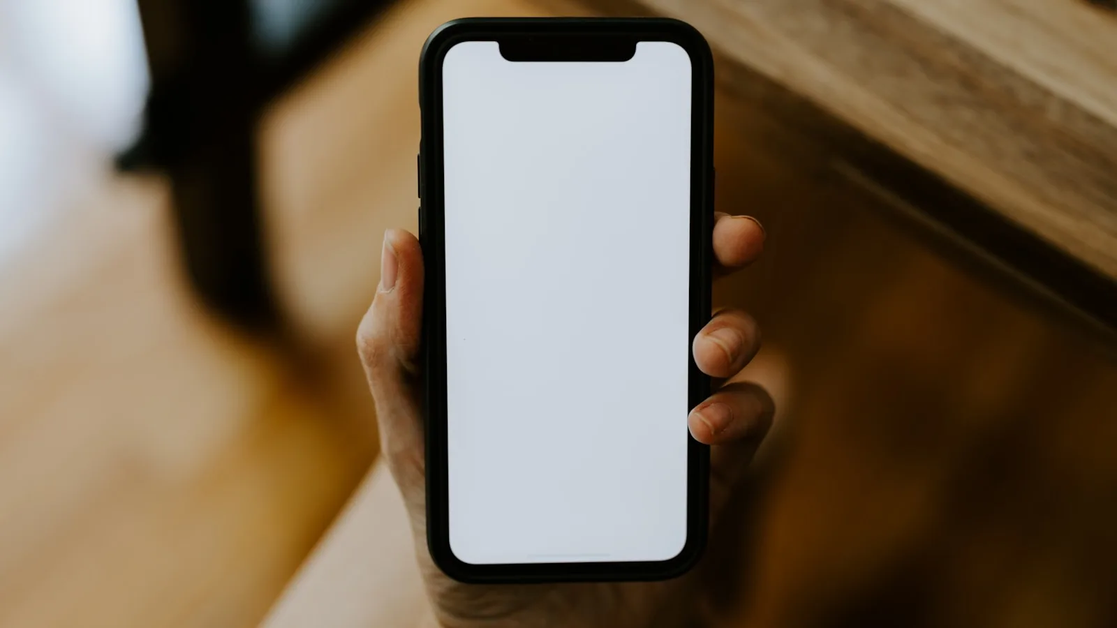 Main tenant un smartphone à l'écran vierge illustrant une application IPTV