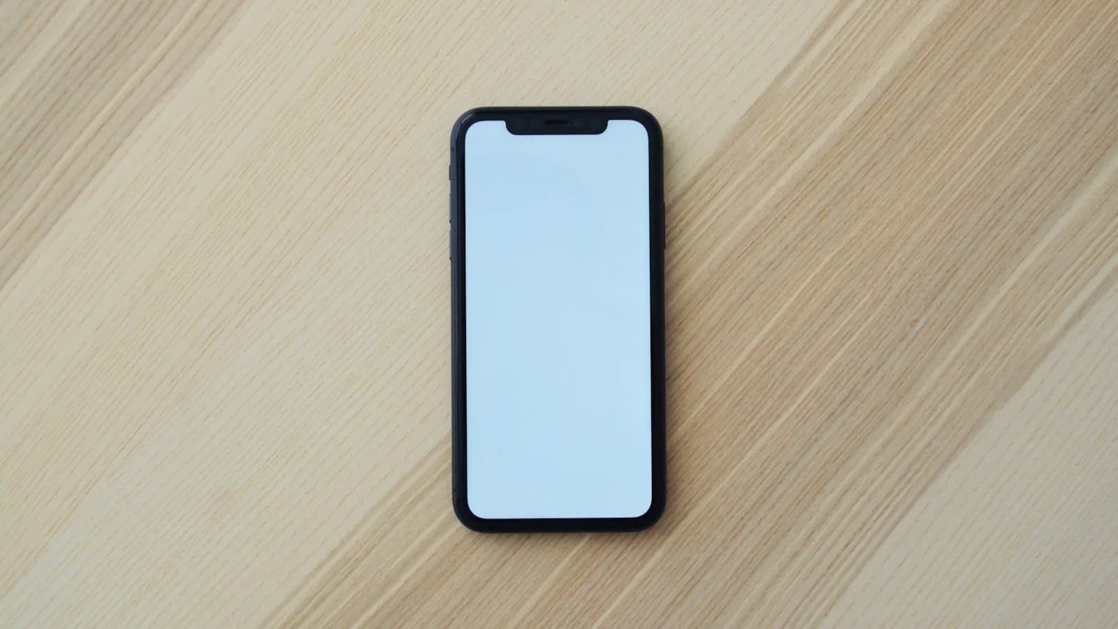 Smartphone à l'écran vierge posé sur une table en bois illustrant les avis sur l'IPTV en France