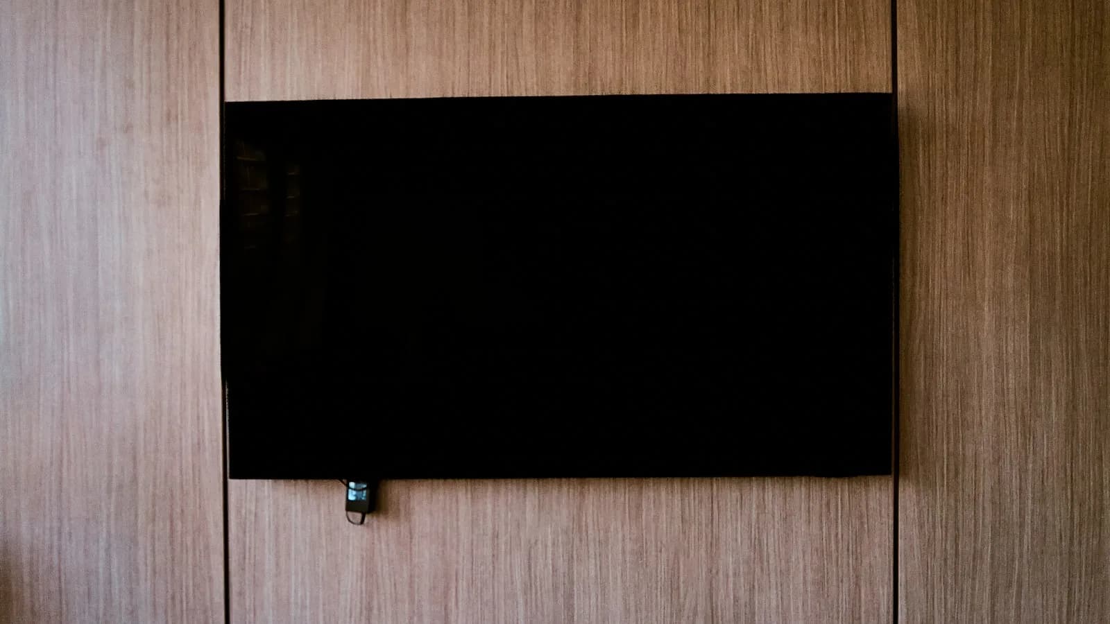 Téléviseur connecté éteint fixé au mur dans un salon en bois